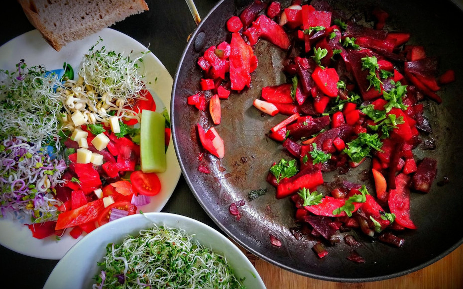 Plates and pan full of colourful food, cut vegetables and sprouted seeds